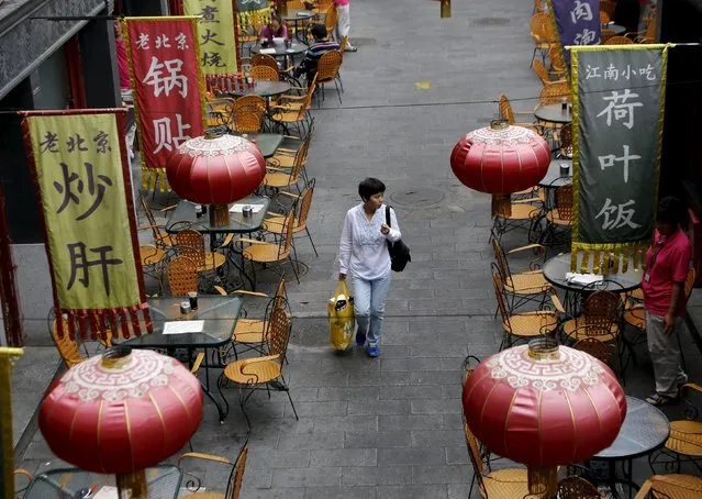 A woman carrying a shopping bag walks underneath lanterns of a restaurant in a shopping district of Beijing, China, September 22, 2015. Pockets of strength in China's economy should help it achieve Beijing's annual growth target for this year, a research paper issued by the country's top economic planner said on Tuesday. (Photo by Kim Kyung-Hoon/Reuters)