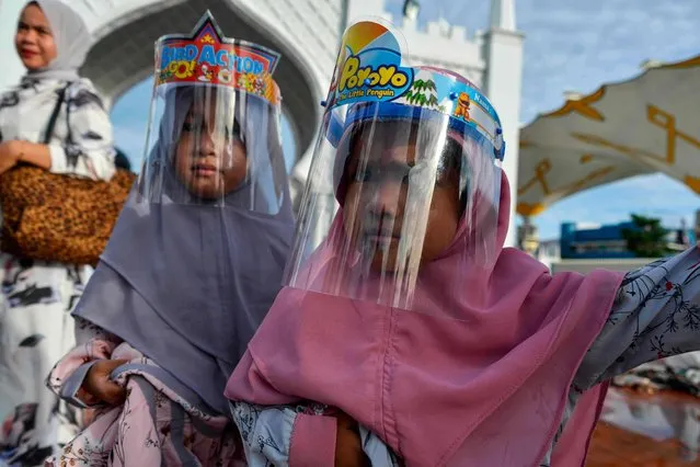 Children wearing face shields attend an Eid al-Adha prayer at the Baiturrahman grand mosque in Banda Aceh on July 31, 2020. (Photo by Chaideer Mahyuddin/AFP Photo)