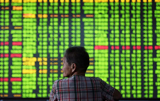 An investor is seen in front of an electronic screen showing stock information at a brokerage house in Hangzhou, Zhejiang Province, China, September 12, 2016. (Photo by Reuters/China Daily)