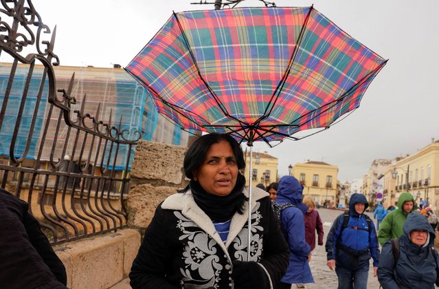 A tourist's umbrella blows upside down as she covers from the heavy rain and high winds, while she tours the city centre, as storm Konrad hits Spain, Portugal and France, in Ronda, Spain, on March 13, 2025. (Photo by Jon Nazca/Reuters)