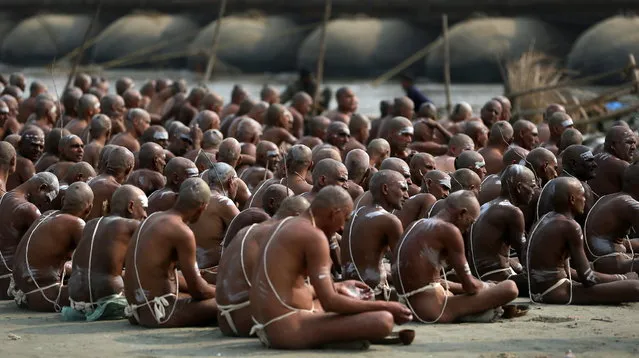 Hindu holy men of the Juna Akhara sect sit after rituals that are believed to rid them of all ties in this life and dedicate themselves to serving God as a “Naga” or naked holy men, at Sangam, the confluence of the Ganges and Yamuna River during the Maha Kumbh festival in Allahabad, India, Wednesday, February 6, 2013. The significance of nakedness is that they will not have any worldly ties to material belongings, even something as simple as clothes. This ritual that transforms selected holy men to Naga can only be done at the Kumbh festival.(Photo by Manish Swarup/AP Photo)