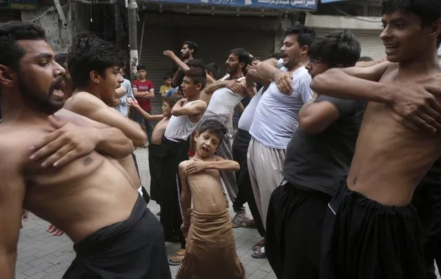A Shiite Muslim boy beat his chest with others during a Muharram procession, in Lahore, Pakistan, Friday, August 28, 2020. Muharram, the first month of the Islamic calendar, is a month of mourning in remembrance of the death of Hussein, the grandson of the Prophet Muhammad, at the Battle of Karbala in present-day Iraq in the 7th century. (Photo by K.M. Chaudary/AP Photo)
