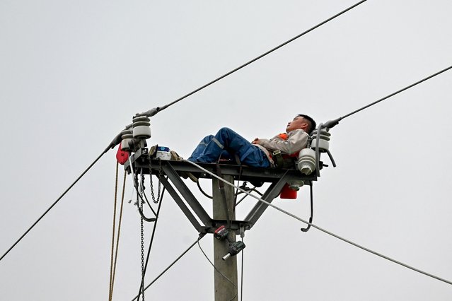 An electricity worker rests as he works on a power line in Hanoi on May 29, 2025. (Photo by Nhac Nguyen/AFP Photo)