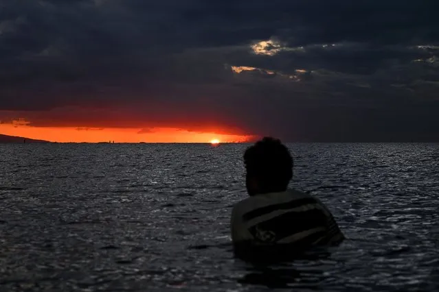 A woman watches the sunset during the low tide in Fiji’s capital city Suva on December 19, 2022. (Photo by Saeed Khan/AFP Photo)
