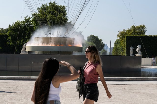 Visitors walk past the Paris 2024 Olympic cauldron designed by French designer Mathieu Lehanneur in Paris on August 11, 2025, amid a heatwave in Europe. The heatwave that started on August 8, 2025 has intensified, with temperatures at an "exceptional level" in the south-west, where 12 departments are classified under red heatwave alert until August 12, 2025 by Meteo-France. (Photo by Martin Lelievre/AFP Photo)
