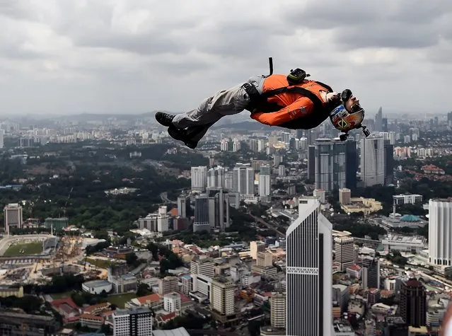Base jumpers leap from the 300-metre high skydeck of Malaysia's landmark Kuala Lumpur Tower against the backdrop of the city's skyline on October 3, 2016 during the annual International KL Tower Base-Jump event. (Photo by Manan Vatsyayana/AFP Photo)