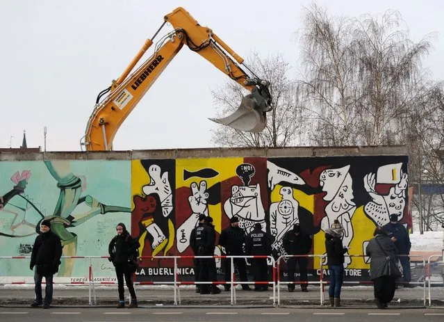 Police officers guard a construction site and sections of the East Side Gallery, while parts of the former Berlin Wall are removed in Berlin, Germany, Wednesday March 27, 2013. Work crews backed by about 250 police have removed portions of the Berlin Wall known as the East Side Gallery to make way for an upscale building project, despite demands by protesters that the site be preserved. Plans to remove part of the 1.3-kilometer (3/4-mile) stretch of wall sparked protests that developers were sacrificing history for profit. (Photo by Britta Pedersen/AP Photo/Dpa)