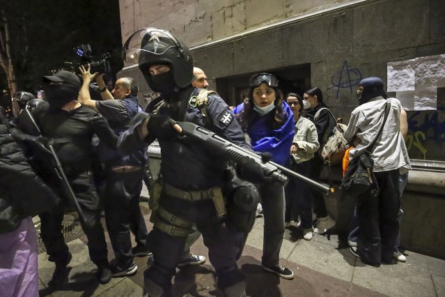 Riot policemen stand ready to fire gas grenade during an opposition protest against “the Russian law” near the Parliament building in Tbilisi, Georgia, on Wednesday, May 1, 2024. Clashes erupted between police and opposition demonstrators protesting a new bill intended to track foreign influence that the opposition denounced as Russia-inspired. (Phoot by Zurab Tsertsvadze/AP Photo)