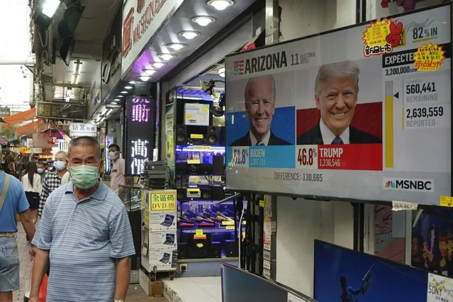 A man walks past a TV monitor showing a news program reporting the U.S. presidential election between President Donald Trump, right, and former Vice President Joe Biden, left, in Hong Kong, Wednesday, November 4, 2020. (Photo by Kin Cheung/AP Photo)