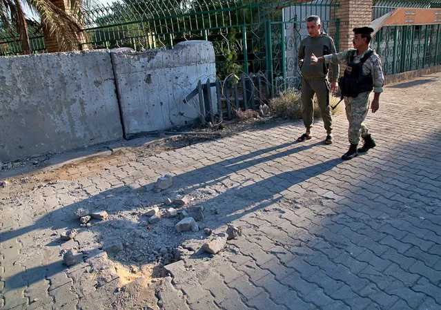 Security forces inspect the scene of the rocket attack at the gate of al-Zawra public park in Baghdad, Iraq, Wednesday, November 18, 2020. Rockets struck Iraq's capital on Tuesday with four landing inside the heavily fortified Green Zone, Iraq's military said, killing a child and wounding at least five people, signaling an end to an informal truce announced by Iran-backed militias in October. (Photo by Khalid Mohammed/AP Photo)