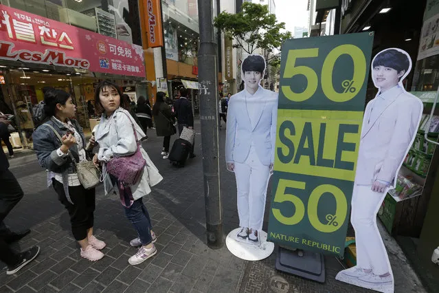 Women stand by a sale sign at a shopping district in Seoul, South Korea, Tuesday, April 19, 2016. South Korea's central bank lowered its growth forecast for Asia's fourth-largest economy on Tuesday, citing the country's weak first-quarter economic performance and a downgrade in the global economic outlook. But it kept its policy rate steady for this month. (Photo by Ahn Young-joon/AP Photo)
