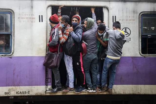 Commuters travel on a local train during a nationwide shutdown called by thousands of Indian farmers protesting new agriculture laws, in Kolkata, India, Tuesday, December 8, 2020. The strike follows five rounds of talks between the farmers and the Indian government that have failed to produce any breakthroughs. The farmers say the laws will lead the government to stop buying grain at minimum guaranteed prices and result in exploitation by corporations that will push down prices. (Photo by Bikas Das/AP Photo)