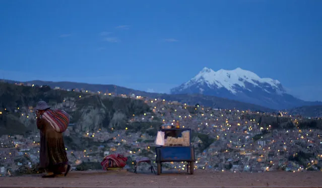 A woman walks along Pereferica Avenue, past a street stall of popcorn, known as “pipocas”, backdropped by the snow-capped Illimani Mountain, at sunset in La Paz, Bolivia, Tuesday, April 24, 2018. Illimani is part of the Cordillera Real in the Andes of South America. (Photo by Juan Karita/AP Photo)