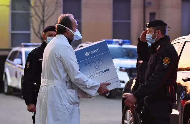 Doctor Giovanni Di Perri receives a box with the Pfizer-BioNTech coronavirus disease (COVID-19) vaccine at Amedeo di Savoia hospital in Turin, Italy, December 27, 2020. (Photo by Massimo Pinca/Reuters)