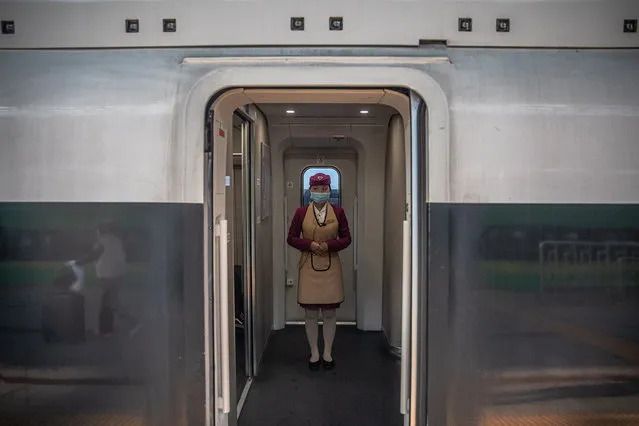 A train attendant wearing a protective face mask stands on a train to Wuhan, at the railway station in Beijing, China, 29 March 2020. Wuhan, the epicenter of the coronavirus outbreak, partly lifted the lockdown allowing people to enter the city after more than two months. Chinese authorities eased the quarantine measures as cases of Covid-19 across China have plummeted, according to Chinese government figures. (Photo by Roman Pilipey/EPA/EFE)