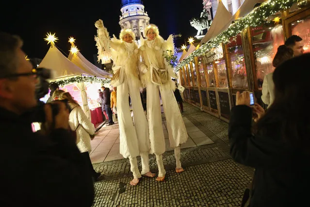 Visitors photograph two performers on stilts at the annual Christmas market at Gendarmenmarkt on its opening day on November 23, 2015 in Berlin, Germany. Christmas markets are opening across Germany this week and though police are on hgh alert following the recent terror attacks in Paris authorities say they will not be posting a strong police presence at the Christmas markets. (Photo by Sean Gallup/Getty Images)