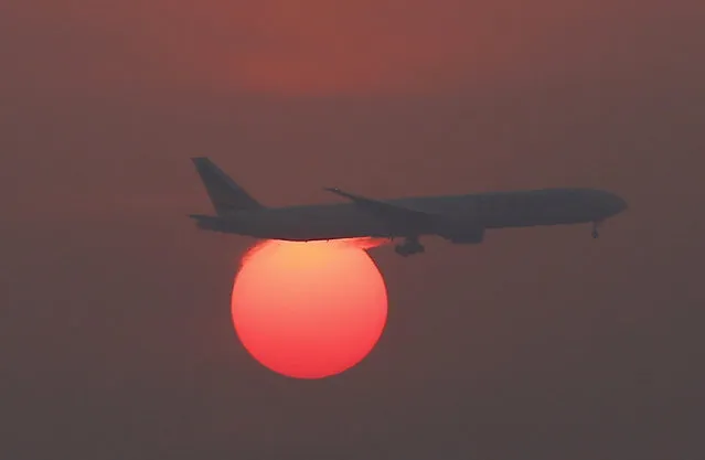 A plane flies over the setting sun in the sky at Beijing International Airport, China, March 2, 2016. (Photo by Kim Kyung-Hoon/Reuters)