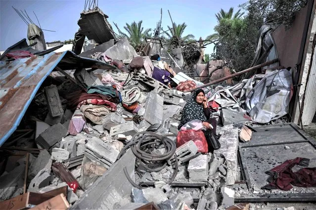A woman sits amidst the rubble of a building hit in an Israeli air strike in Biet Hanoun, in the northern Gaza Strip, on May 12, 2023. Israel's military launched further strikes on Gaza on May 12 after militants fired rockets from the territory, on the fourth day of fighting which has killed dozens of Palestinians and one in Israel. (Photo by Mohammed Abed/AFP Photo)