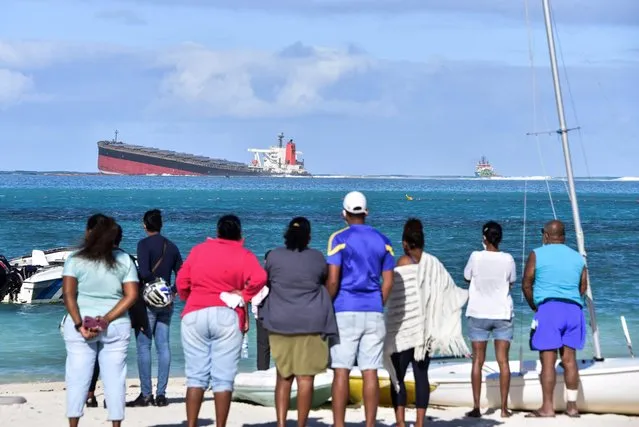 Bystanders look at MV Wakashio bulk carrier that had run aground and from which oil is leaking near Blue Bay Marine Park in south-east Mauritius on August 6, 2020. The carrier, belonging to a Japanese company but Panamanian-flagged, ran aground on July 25 and its crew was evacuated safely. The ship was empty at the time but was carrying 200 tonnes of diesel and 3,800 tonnes of bunker fuel, according to the local press. (Photo by Dev Ramkhelawon/L'Express Maurice/AFP Photo)