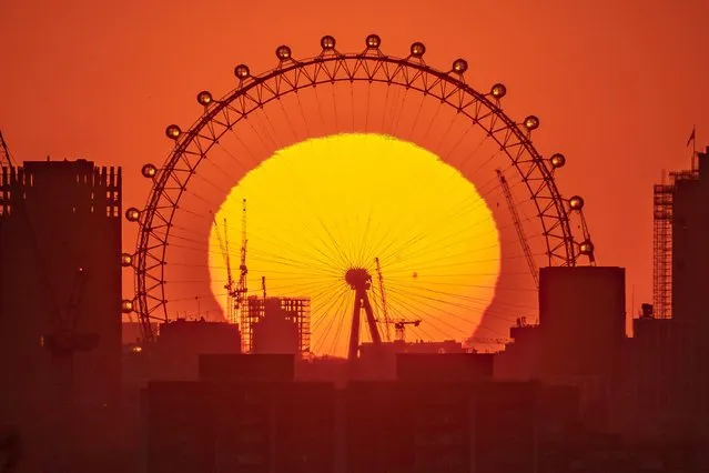 Dramatic evening sun sets behind The London Eye ferris wheel viewed from top of Greenwich Park on April 19, 2023. (Photo by Guy Corbishley/Alamy Live News)