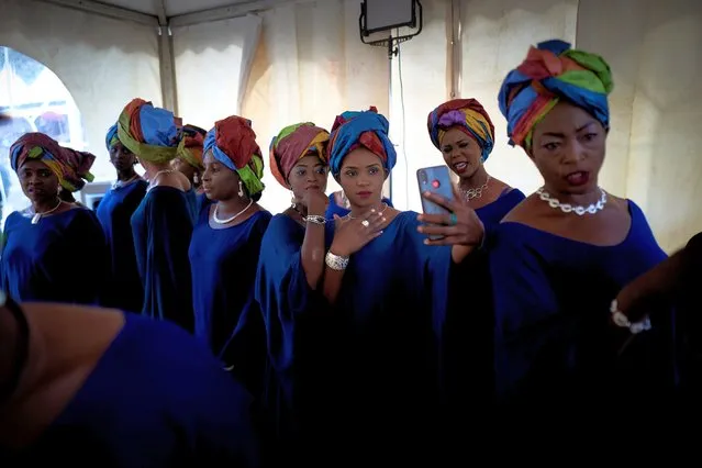 Two Gold diggers take selfie pictures with their mobile phone while waiting in the backstage for the start of the fashion show as part of the first edition of the International Gold Fair, in Bamako, on February 12, 2021. The Princess of Burundi, selected 34 women among gold mines workers in southern Mali, to walk down the catwalk for a fashion show organised during the International Gold Fair. Gold represents 15% of Mali's exports and more than 20% of its GDP estimated at nearly US$20 billion by the end of 2019. (Photo by Michele Cattani/AFP Photo)