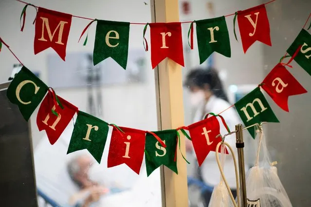 A holiday greeting hangs as a healthcare worker checks on a patient inside the COVID-19 unit at Trinitas Regional Medical Center in Elizabeth, New Jersey, December 16, 2020. (Photo by Eduardo Munoz/Reuters)
