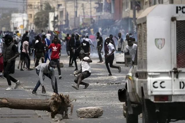 Demonstrators clash with riot policemen during protests against the arrest of opposition leader and former presidential candidate Ousmane Sonko in Dakar, Senegal, Friday, March 5, 2021. Days of violent protests in Senegal have killed at least one person, local reports say, as young people take to the streets nationwide in support of the main opposition leader who was detained Wednesday. (Photo by Leo Correa/AP Photo)