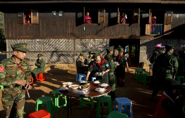 In this Jan. 12, 2015 photo, monks take pictures with their mobile phone cameras as a female officer of the Ta’ang National Liberation army (TNLA) prepares breakfast for visiting rebel leaders at Mar Wong Village in northern Shan state, Myanmar, to mark the 52nd anniversary of their insurrection. (Photo by Gemunu Amarasinghe/AP Photo)