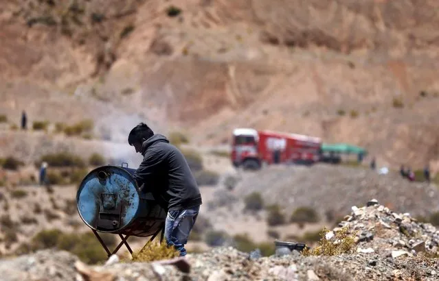 A man cooks on a grill made out of a gasoline tank as a truck arrives at the starting line of the fourth stage of the Dakar Rally 2016 in Jujuy province, Argentina, January 6, 2016. (Photo by Marcos Brindicci/Reuters)