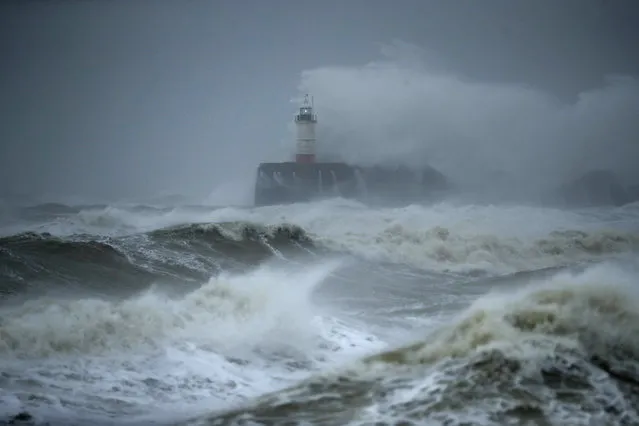 Waves crash over the harbour and a lighthouse, as Storm Ciara hits Newhaven, on the south coast of England, Sunday, February 9, 2020. Trains, flights and ferries have been cancelled and weather warnings issued across the United Kingdom and in northern Europe as the storm with winds expected to reach hurricane levels batters the region. (Photo by Matt Dunham/AP Photo)
