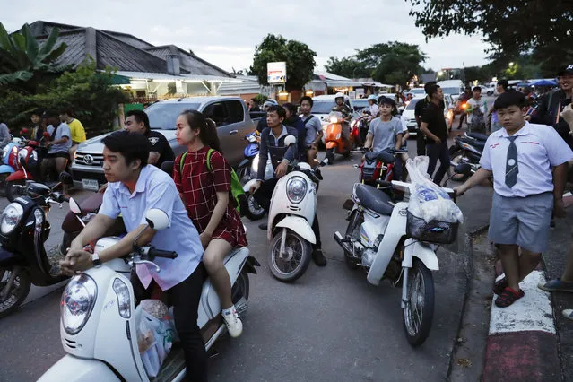 People wait as police block the road during an emergency helicopter evacuation in Chiang Rai as divers evacuated some of the 12 boys and their coach trapped at Tham Luang cave in the Mae Sai district of Chiang Rai province, northern Thailand, Tuesday, July 10, 2018. Thai Navy SEALs say all 12 boys and their coach were rescued from the cave, ending an ordeal that lasted more than 2 weeks. (Photo by Vincent Thian/AP Photo)