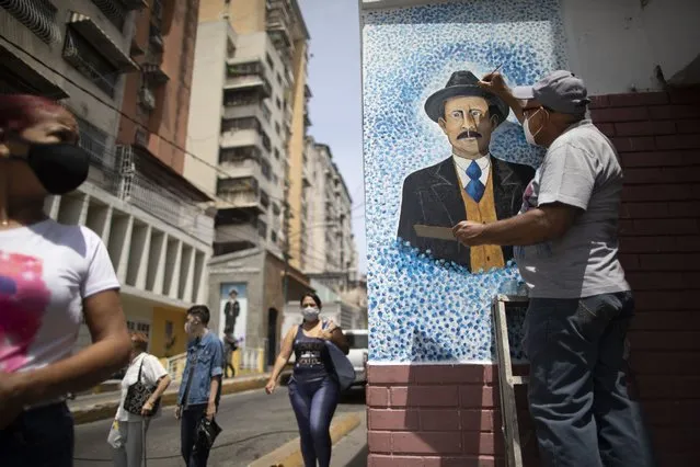 Venezuelan artist Mervin Marmol puts finishing touches on his painting of late Venezuelan Dr. Jose Gregorio Hernandez at the street corner where he died in a car accident in 1919 in La Pastora neighborhood in Caracas, Venezuela, Monday, April 26, 2021. (Photo by Ariana Cubillos/AP Photo)