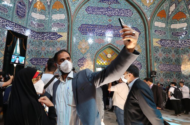 An Iranian voter takes a selfie at a mosque turned polling station druing voting in Iran's presidential election in the capital Tehran, on June 18, 2021. Iranian voters cast their ballots today in a presidential election in which ultraconservative cleric Ebrahim Raisi is seen all but certain to coast to victory after all serious rivals were barred from running. (Photo by Atta Kenare/AFP Photo)