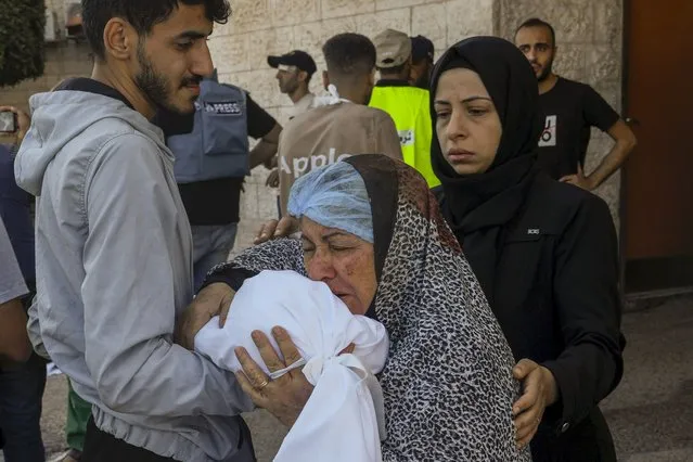 A Palestinian woman kisses the sheet-covered body of a child killed during an Israeli airstrike, Sunday, October 15, 2023, outside al-Aqsa Hospital in Deir el-Balah, central Gaza Strip. (Photo by Adel Hana/AP Photo)
