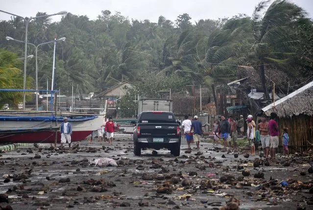 Debris litter the road by the coastal village in Legazpi city following a storm surge brought about by powerful Typhoon Haiyan in Albay province Friday, November 8, 2013, about 520 kilometers ( 325 miles) south of Manila, Philippines. (Photo by Nelson Salting/AP Photo)