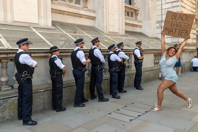 Metropolitan police officers on Whitehall in London, United Kingdom look on as a woman holds a placard supporting the Black Lives Matter movement on May 31, 2020. The demonstration was sparked by the death of George Floyd while being arrested by US police. (Photo by Ray Tang/The Guardian)