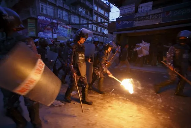 A Nepalese riot police personnel tries to douse a torch confiscated from the protester during the torch rally in Kathmandu April 6, 2015. (Photo by Navesh Chitrakar/Reuters)