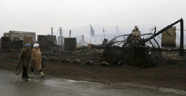 Women walk near the debris of burnt buildings in the settlement of Shyra, damaged by recent wildfires, in Khakassia region, April 13, 2015. (Photo by Ilya Naymushin/Reuters)