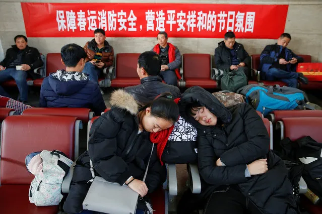 Passengers rest in front of a banner urging for fire protection during the Spring Festival at the departure hall of the Beijing Railway Station in central Beijing, China January 13, 2017 as the annual festival travel rush begins ahead of the Chinese Lunar New Year. (Photo by Damir Sagolj/Reuters)