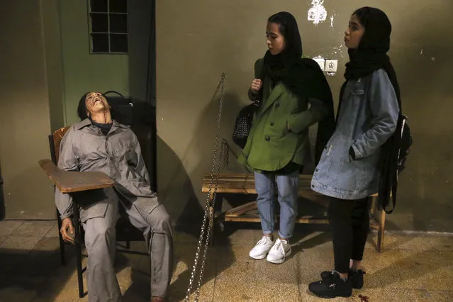 In this Monday, January 7, 2019 photo, women look at an exhibition at a former prison run by the pre-revolution intelligence service, SAVAK, now a museum, where a wax mannequin of a tortured female prisoner is on display, in downtown Tehran, Iran. As Iran marks the 40th anniversary of its Islamic Revolution and the overthrow of the shah, those who suffered torture at the hands of the police and dreaded SAVAK still bear the scars. U.N. investigators and rights group say that even today, Iran tortures and arbitrarily detains prisoners. (Photo by Ebrahim Noroozi/AP Photo)