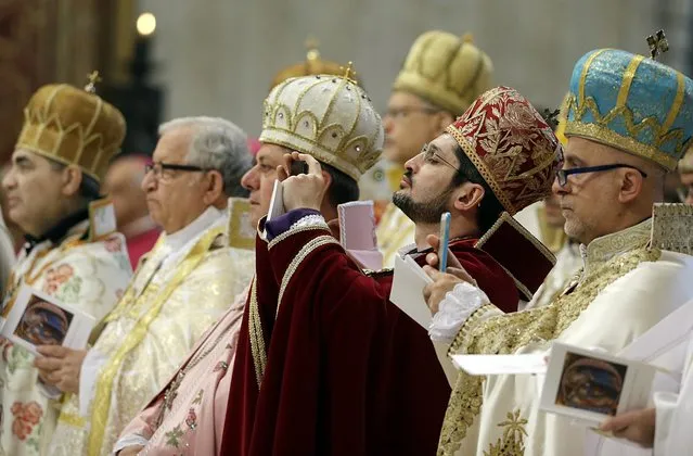 Prelates take pictures as Pope Francis celebrates an Armenian-Rite Mass to commemorate the 100th anniversary of the Armenian Genocide, in St. Peter's Basilica, at the Vatican Sunday, April 12, 2015. Historians estimate that up to 1.5 million Armenians were killed by Ottoman Turks around the time of World War I, an event widely viewed by genocide scholars as the first genocide of the 20th century. (Photo by Gregorio Borgia/AP Photo)