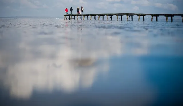 People stand on a pier on the Jade Bight in Gangast, 28 February 2016. The sunshine drew hundereds of visitors to the North Sea coast on Sunday. (Photo by Julian Stratenschulte/EPA)