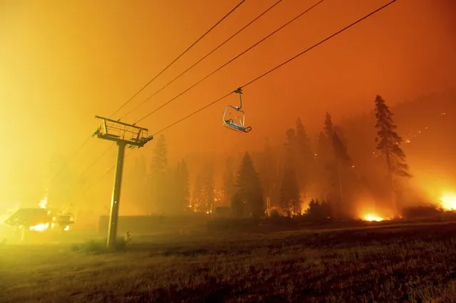 Seen in a long camera exposure, the Caldor Fire burns at the Sierra-at-Tahoe ski resort on Sunday, August 29, 2021, in Eldorado National Forest, Calif. The main buildings at the ski slope's base survived as the main fire front passed. (Photo by Noah Berger/AP Photo)