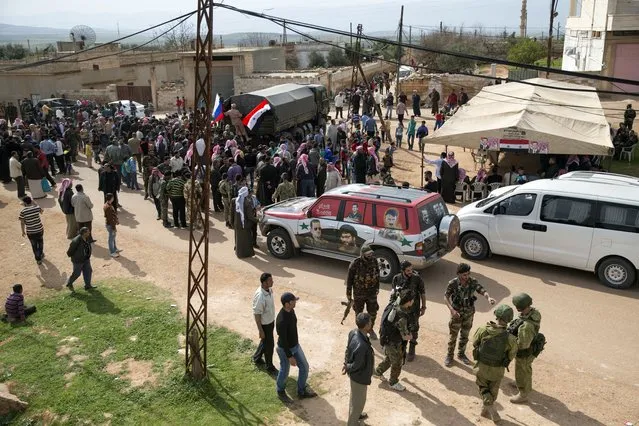 People gather around a Russian military truck to receive a food aid in Maarzaf, about 15 kilometers west of Hama, Syria, Wednesday, March 2, 2016. (Photo by Pavel Golovkin/AP Photo)