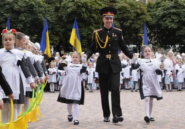 A cadet and schoolgirls run as they ring a symbolic bell, during a ceremony on the occasion of the first day in school at a cadet lyceum in Kyiv, Ukraine, Wednesday, September 1, 2021. Ukraine marks Sept. 1 as Knowledge Day, as a traditional launch of the academic year. (Photo by Efrem Lukatsky/AP Photo)