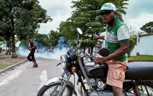 A moto-taxi driver reacts as riot police fire teargas towards anti-government protesters gathered to mourn in the neighborhood of veteran Congolese opposition leader Etienne Tshisekedi of the Union for Democracy and Social Progress (UDPS) in the Limete Municipality of the Democratic Republic of Congo's capital Kinshasa, February 2, 2017. (Photo by Robert Carrubba/Reuters)