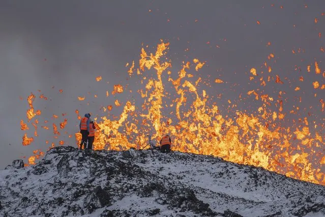 Scientist of the University of Iceland take measurements and samples standing on the ridge in front of the active part of the eruptive fissure of an active volcano in Grindavik on Iceland's Reykjanes Peninsula, Tuesday, December 19, 2023. (Photo by Marco Di Marco/AP Photo)