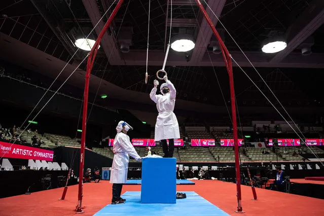 Staff members disinfect the rings as a preventive measure against the Covid-19 coronavirus during the Artistic Gymnastics World Championships at the Kitakyushu City Gymnasium in Kitakyushu, Fukuoka prefecture on October 20, 2021. (Photo by Philip Fong/AFP Photo)