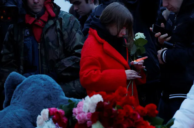 A woman holds a candle at a makeshift memorial to the victims of a shooting attack set up outside the Crocus City Hall concert venue in the Moscow Region, Russia, on March 23, 2024. (Photo by Maxim Shemetov/Reuters)