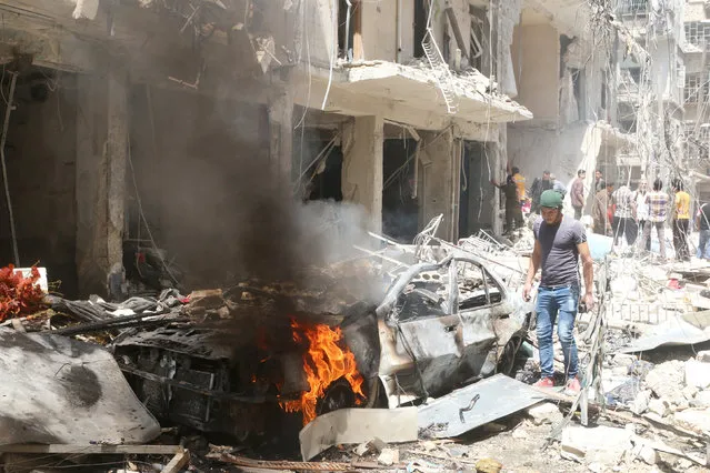 People inspect the damage at a site hit by airstrikes, in the rebel-held area of Aleppo's Bustan al-Qasr, Syria April 28, 2016. (Photo by Abdalrhman Ismail/Reuters)